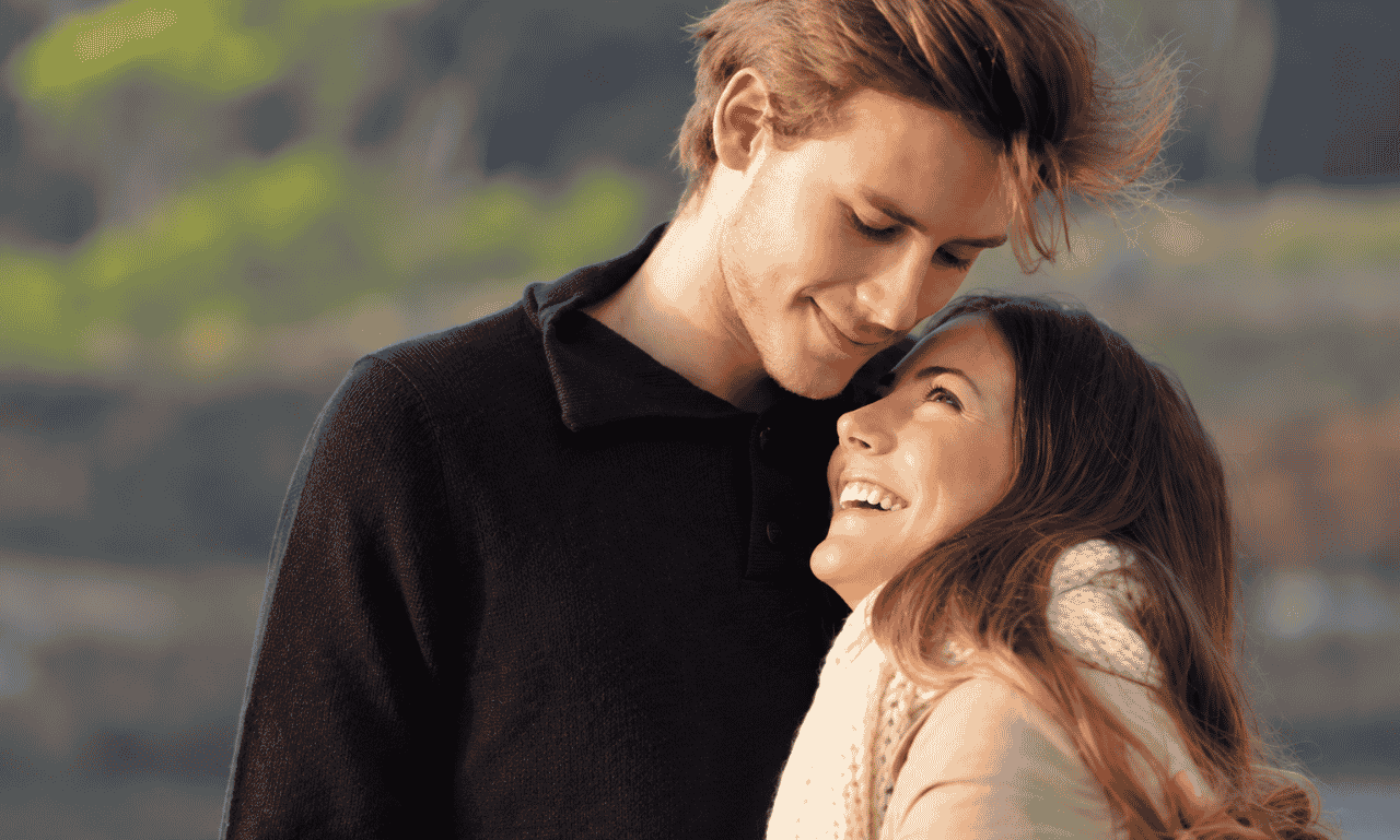 Romantic couple sharing loving smiles outdoors, capturing sweet crush quotes for his smile and heartfelt feelings.